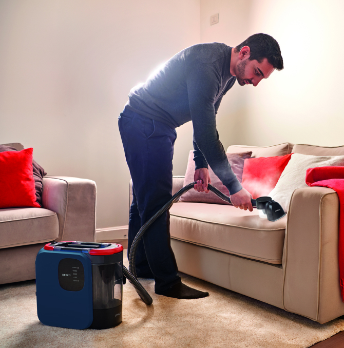 a guy cleaning a sofa with steam